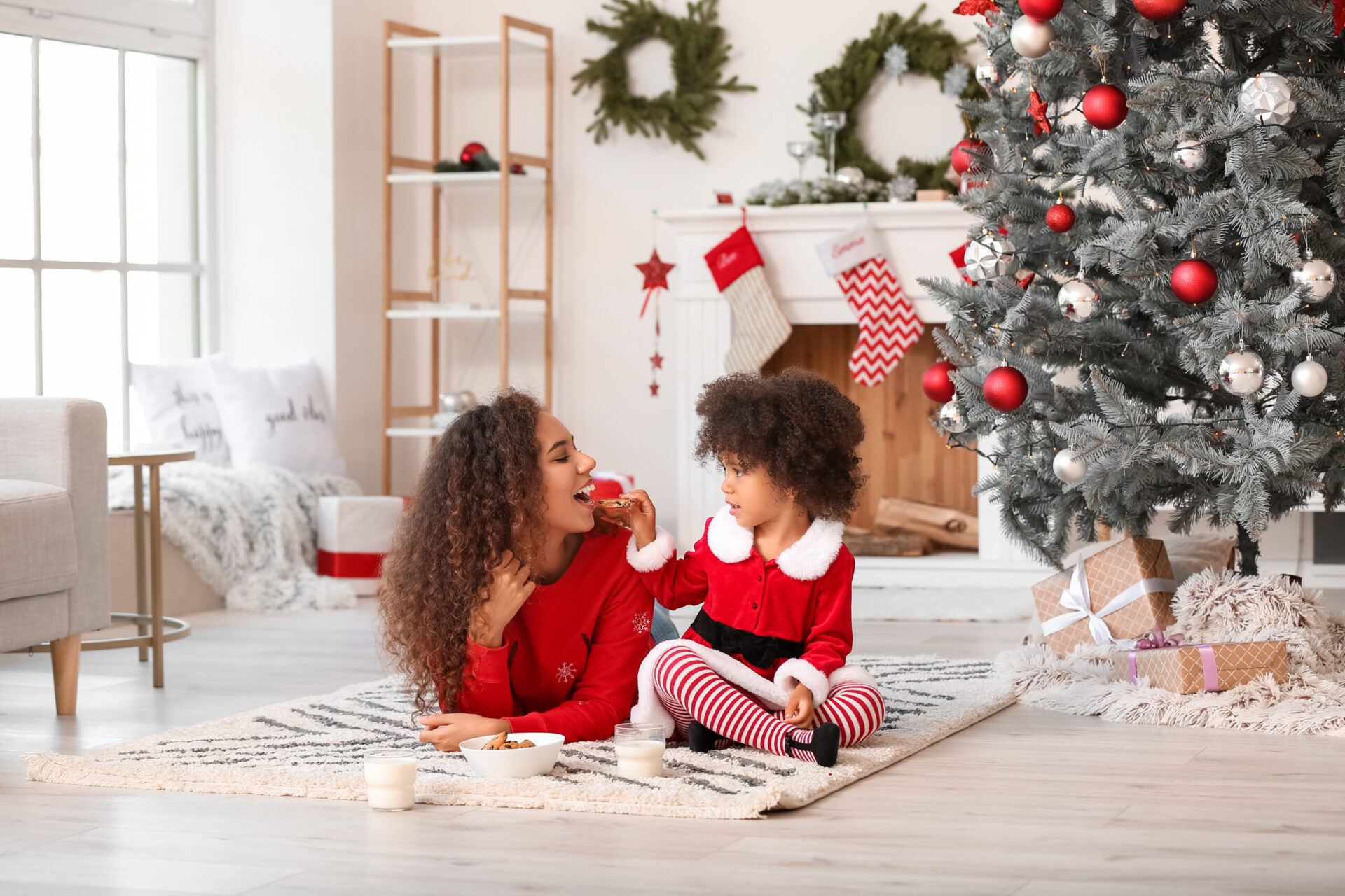 Cute kids sitting in front of the Christmas tree on the hardwood floor